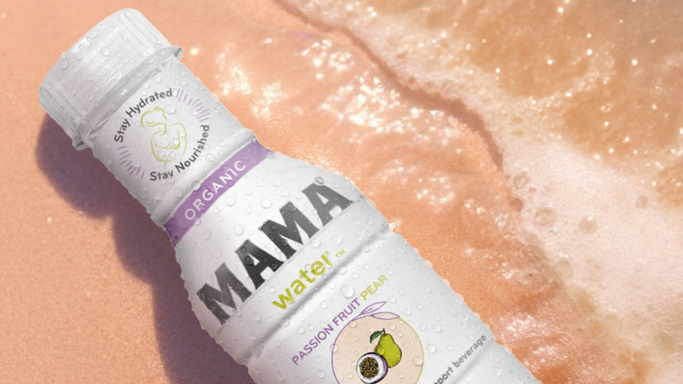 Mama Water bottle on a beach with ocean waves in the background