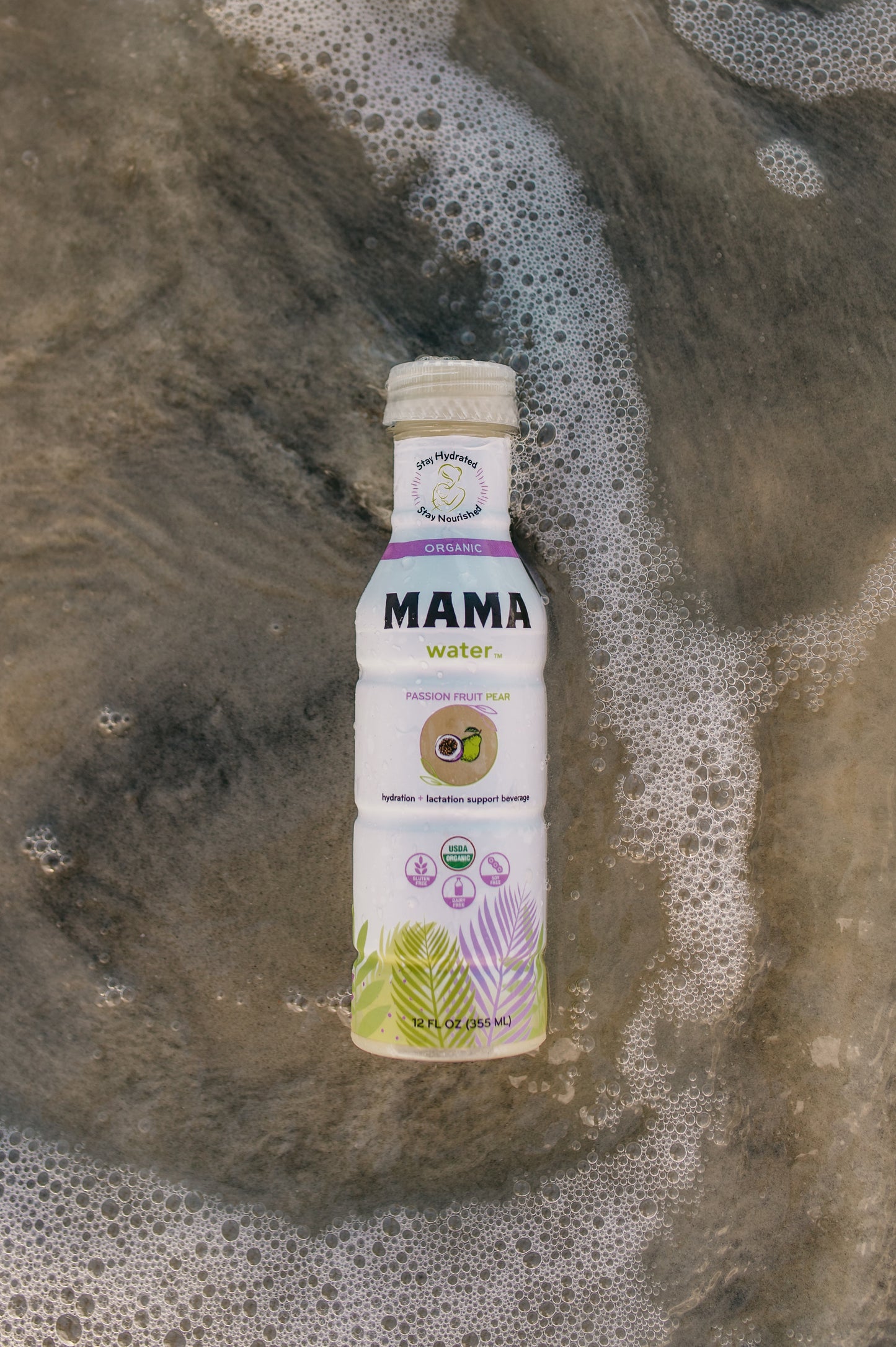 Bottle of MAMA water on a textured surface with water droplets