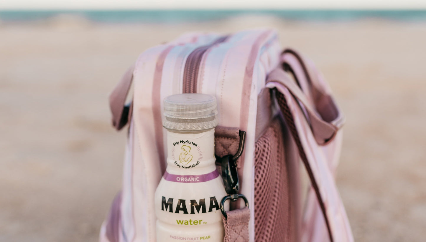 Striped backpack with a bottle labeled 'Mama' on a sandy surface